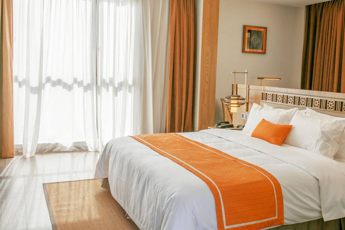 Een hotelkamer met een groot bed, een nachtkastje, een lamp en een schilderij aan de muur.