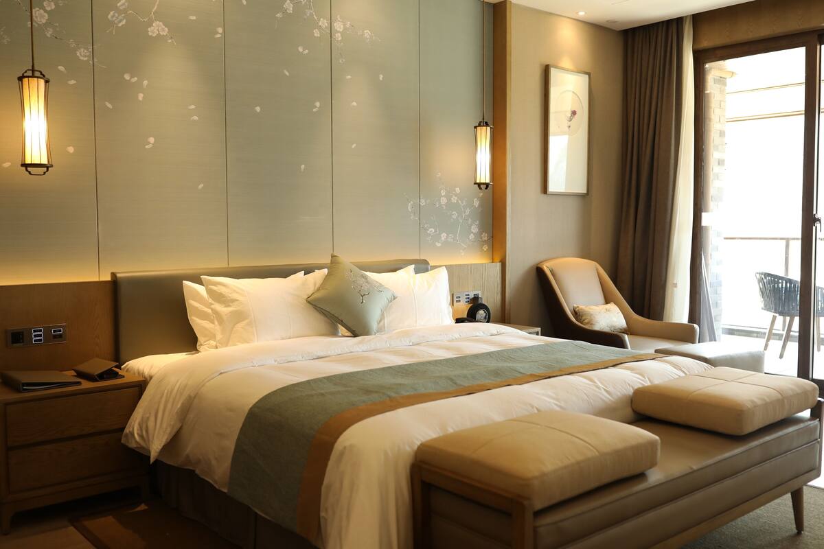Een moderne hotelkamer met een groot bed, een nachtkastje, een stoel en uitzicht op de omgeving.