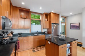 A modern kitchen with wooden cabinets, stainless steel appliances, and a black countertop.