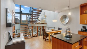 A modern kitchen with a wooden island, a dining area, and a staircase leading to an upper level. - LOVELY VIEWS from this beautiful modern townhome in DT Hood River!! (Hood River)