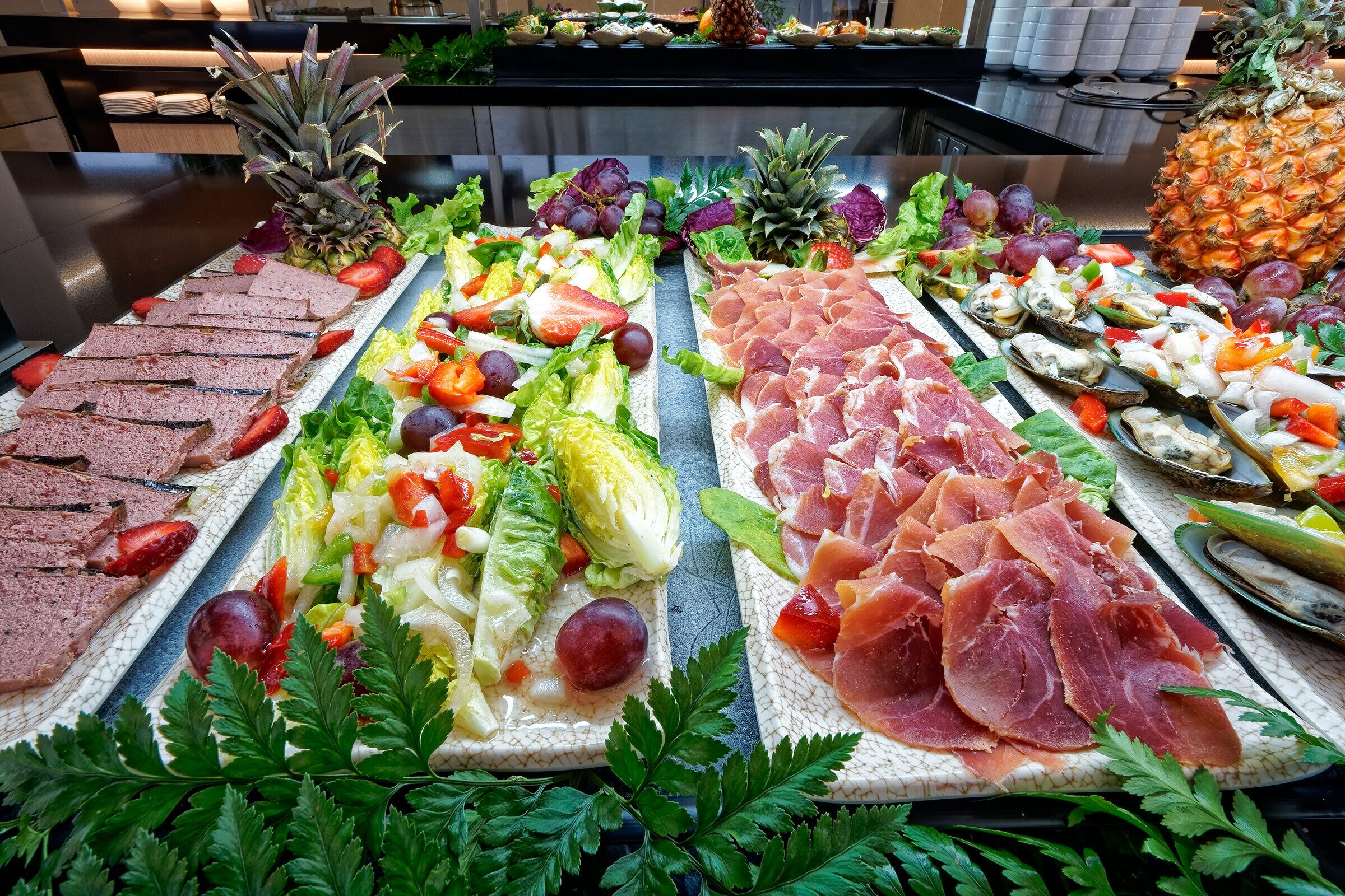 Een buffet met diverse gerechten, waaronder vlees, fruit en groenten.
