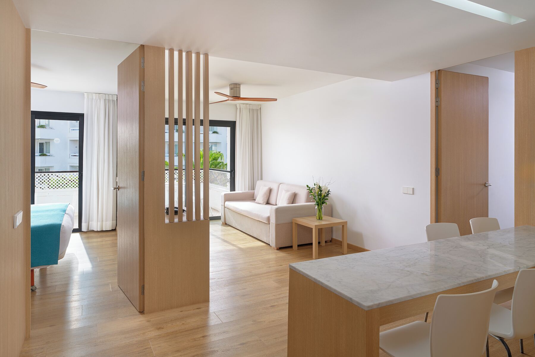 Una sala moderna con un sofá, una mesa de comedor con sillas y vistas al balcón.