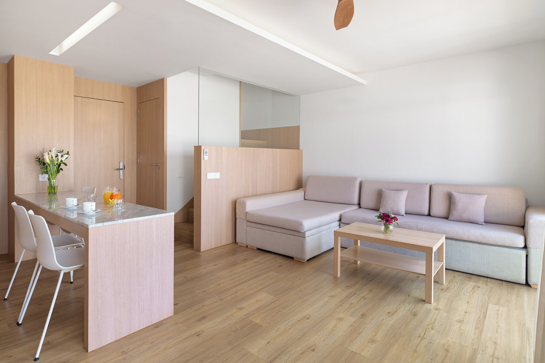 A modern living space with a kitchen area, a dining table, and a sofa.