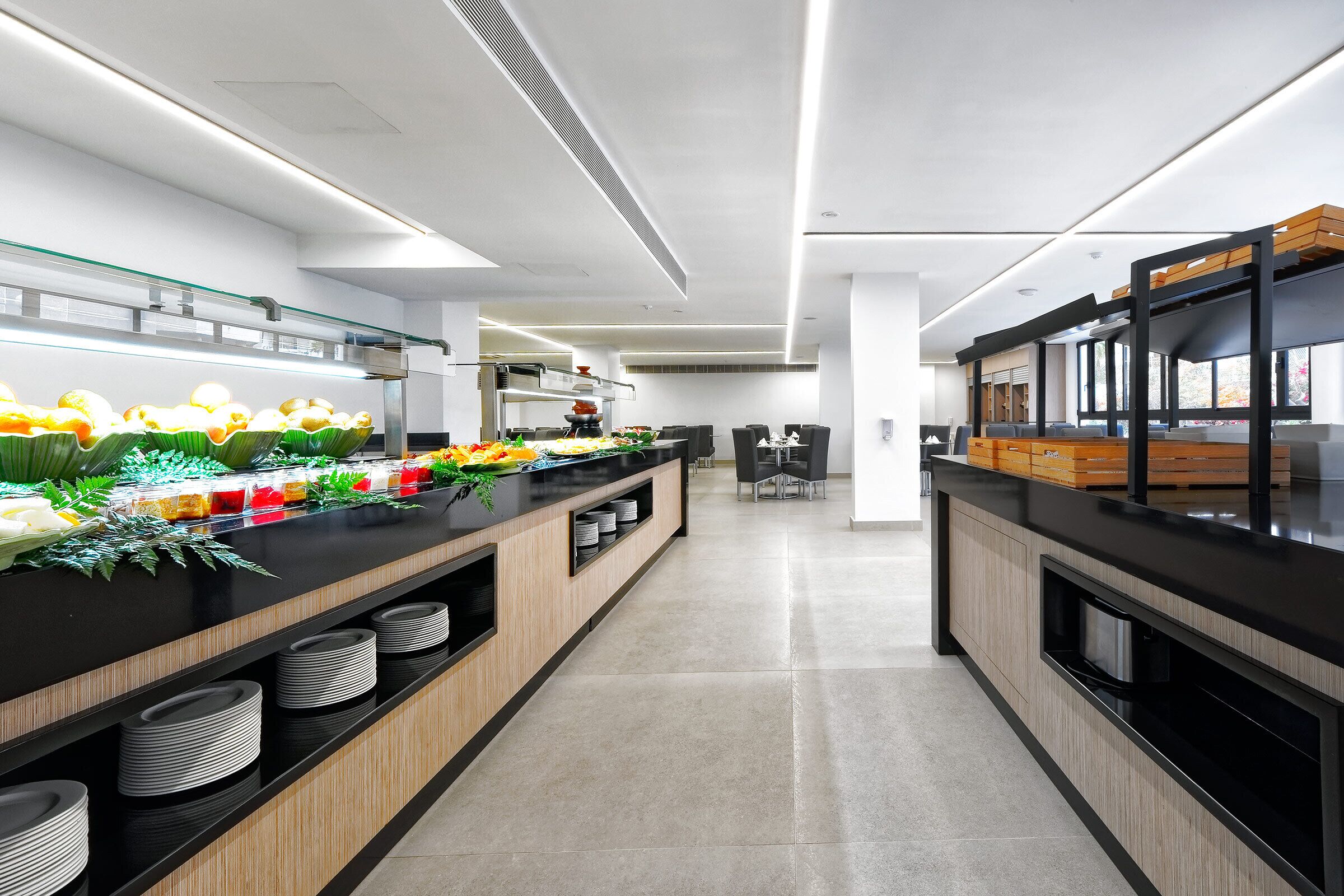 Una cocina moderna con una encimera larga, diversos alimentos y una zona de estar al fondo.