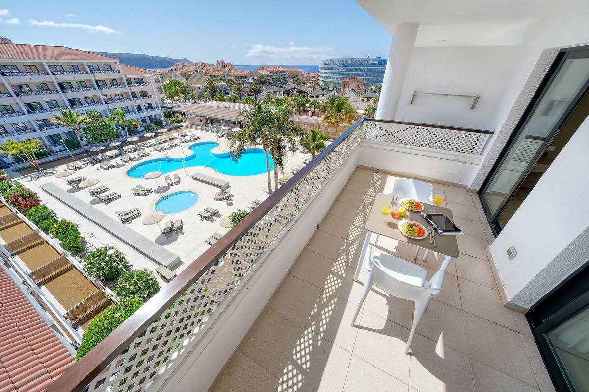 A balcony with a pool view, outdoor seating, and a dining area.