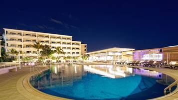 A hotel with a swimming pool, multiple floors, and outdoor seating areas.