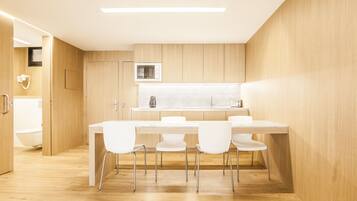 A modern kitchen with a wooden countertop, white chairs, and a built-in microwave.