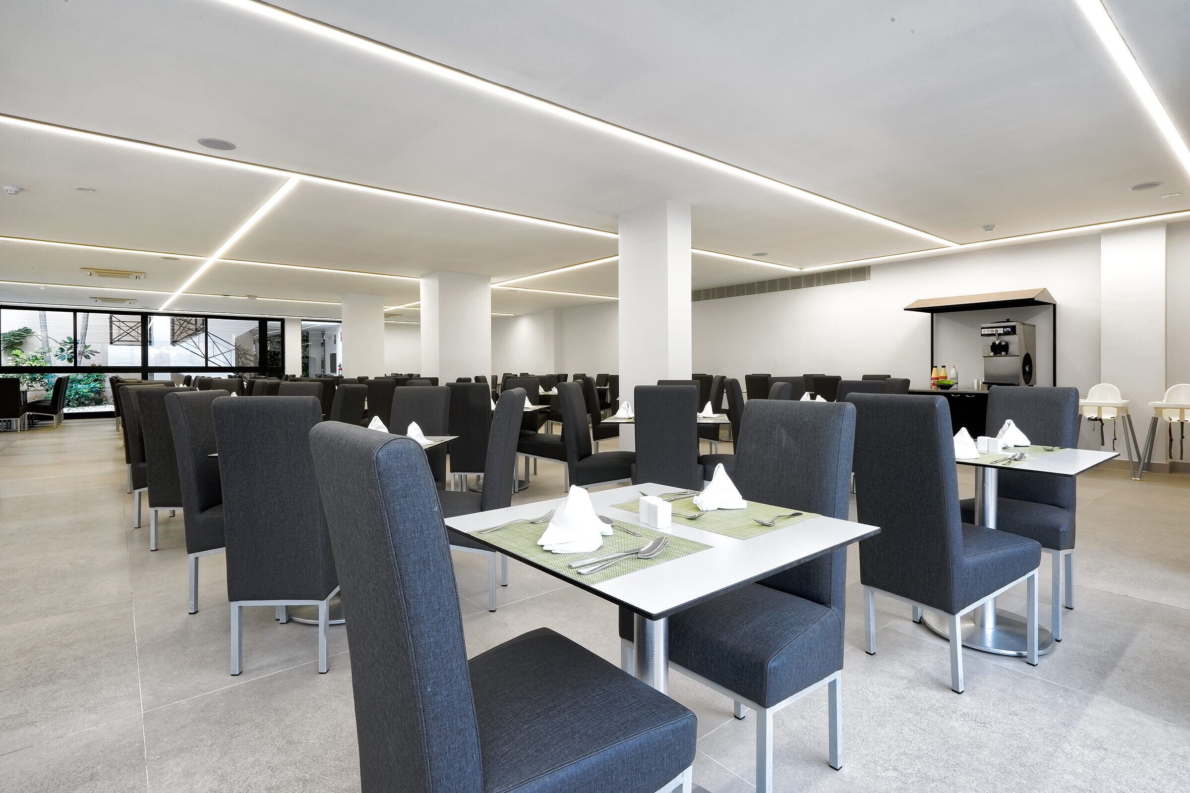 A spacious dining area with modern chairs and tables, large windows, and a clean, minimalist design.