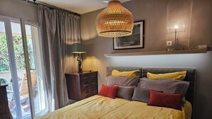 Ein Schlafzimmer mit einem Bett, einer Kommode, einer Lampe, einer Pendelleuchte und einem gerahmten Bild an der Wand.