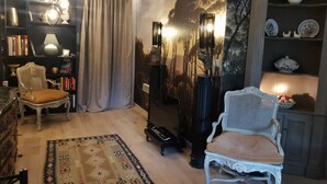 Ein gemütliches Wohnzimmer mit Klavier, Bücherregal, einem gemusterten Teppich und Wanddekoration.