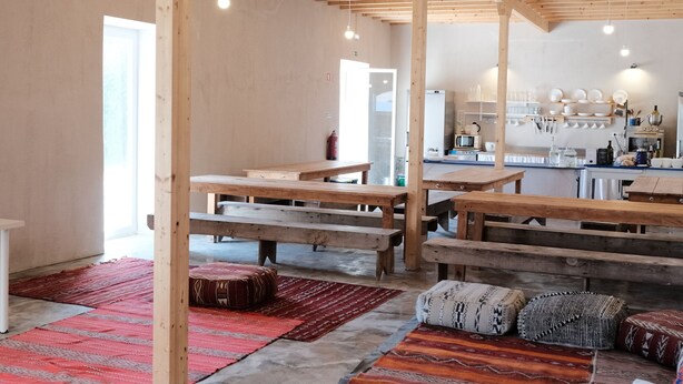A spacious room with wooden beams, benches, and a kitchen area. - Azoia 10 (Santarém)