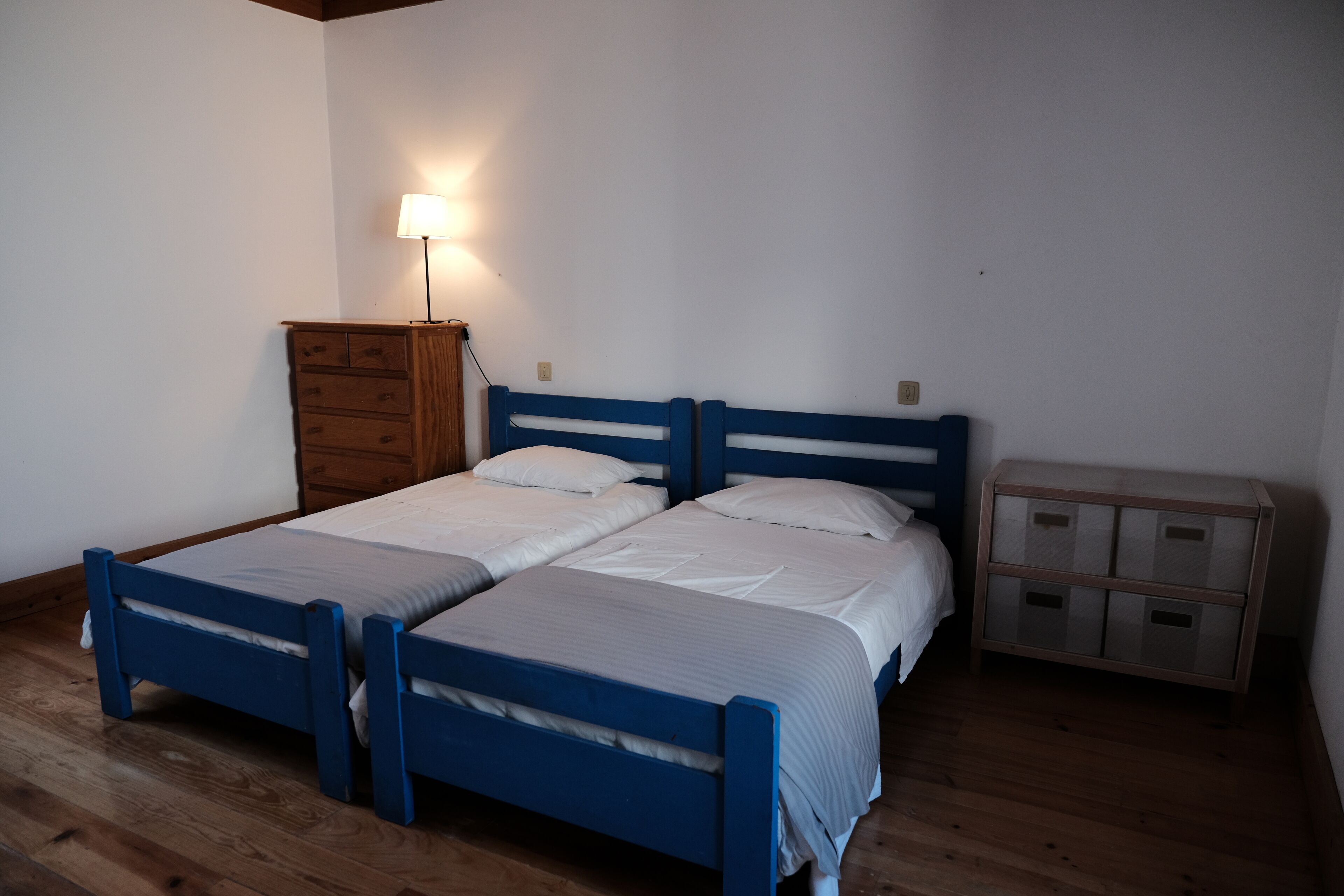 Una habitación con dos camas, un aparador de madera y una mesita de noche con cajones.
