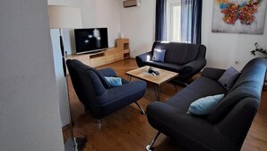 A modern living room with a flat-screen TV, a sofa, a coffee table, and a painting on the wall. - Apartment for five people with a terrace (Pula)