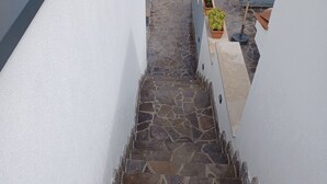 A stone staircase leading to a rooftop area with a grassy lawn and a grey umbrella. - Apartment for five people with a terrace (Pula)