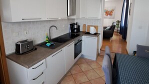 A compact kitchen with white cabinets, a stainless steel range hood, a toaster, and a sink. - Apartment for five people with a terrace (Pula)