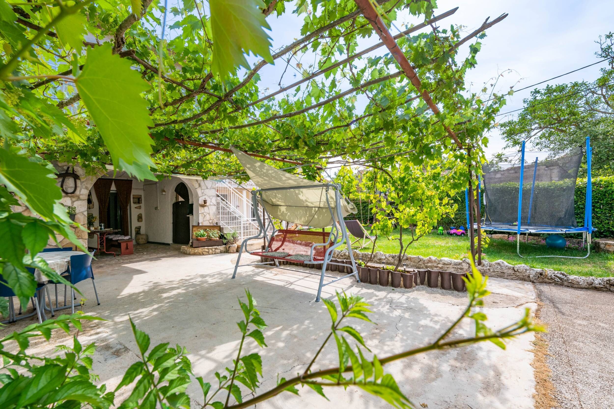 A patio area with a table and chairs, a swing set, and a trampoline.