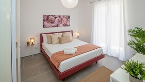 Un dormitorio con una cama, lámparas de noche, una obra de arte en la pared y una planta en maceta.