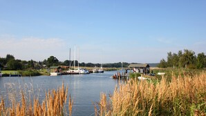 Un lago tranquilo con barcos amarrados, rodeado de zonas verdes y árboles.