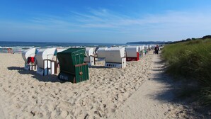 Una playa con hileras de cabañas blancas y una silla verde.