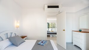 Un dormitorio con cama, mesita de noche, cómoda y espejo.