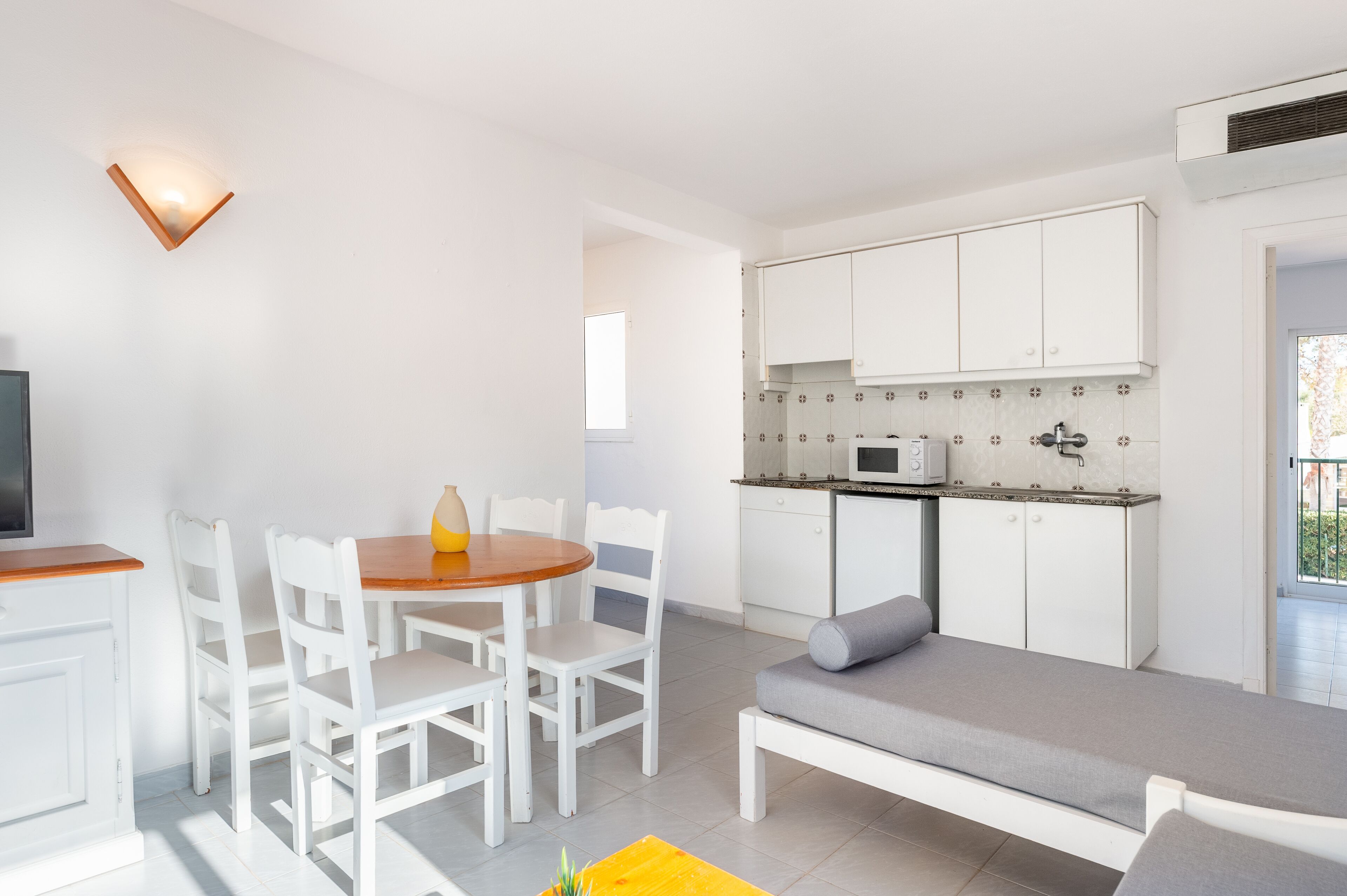 A compact living space with a dining area, kitchenette, and a sofa.