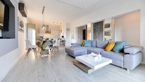 Una sala de estar moderna con un sofá gris, una mesa de centro y una zona de comedor con sillas y una mesa.