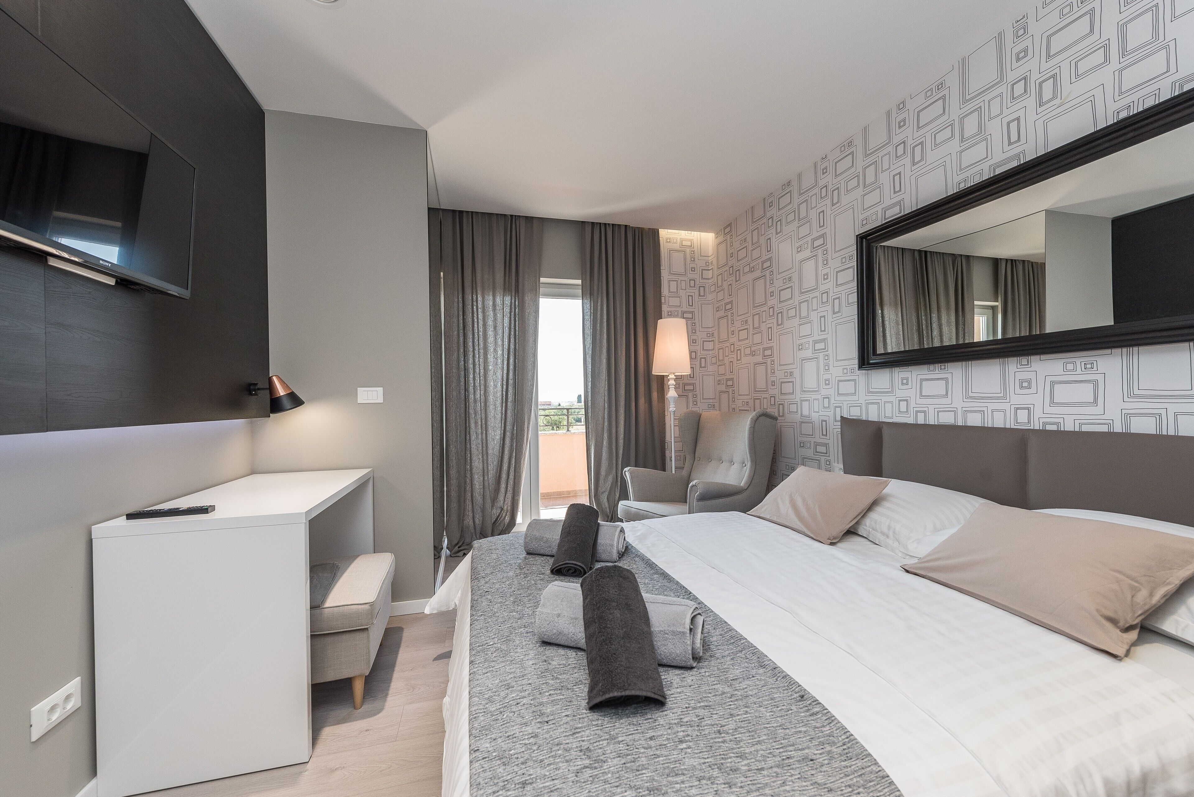 Et moderne hotelværelse med seng, skrivebord, stol og fjernsyn.