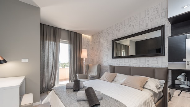 Une chambre d’hôtel moderne avec un grand lit, un bureau, une chaise et un grand miroir.