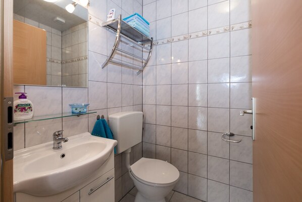 A bathroom with a white sink, a toilet, a mirror, and a towel rack.