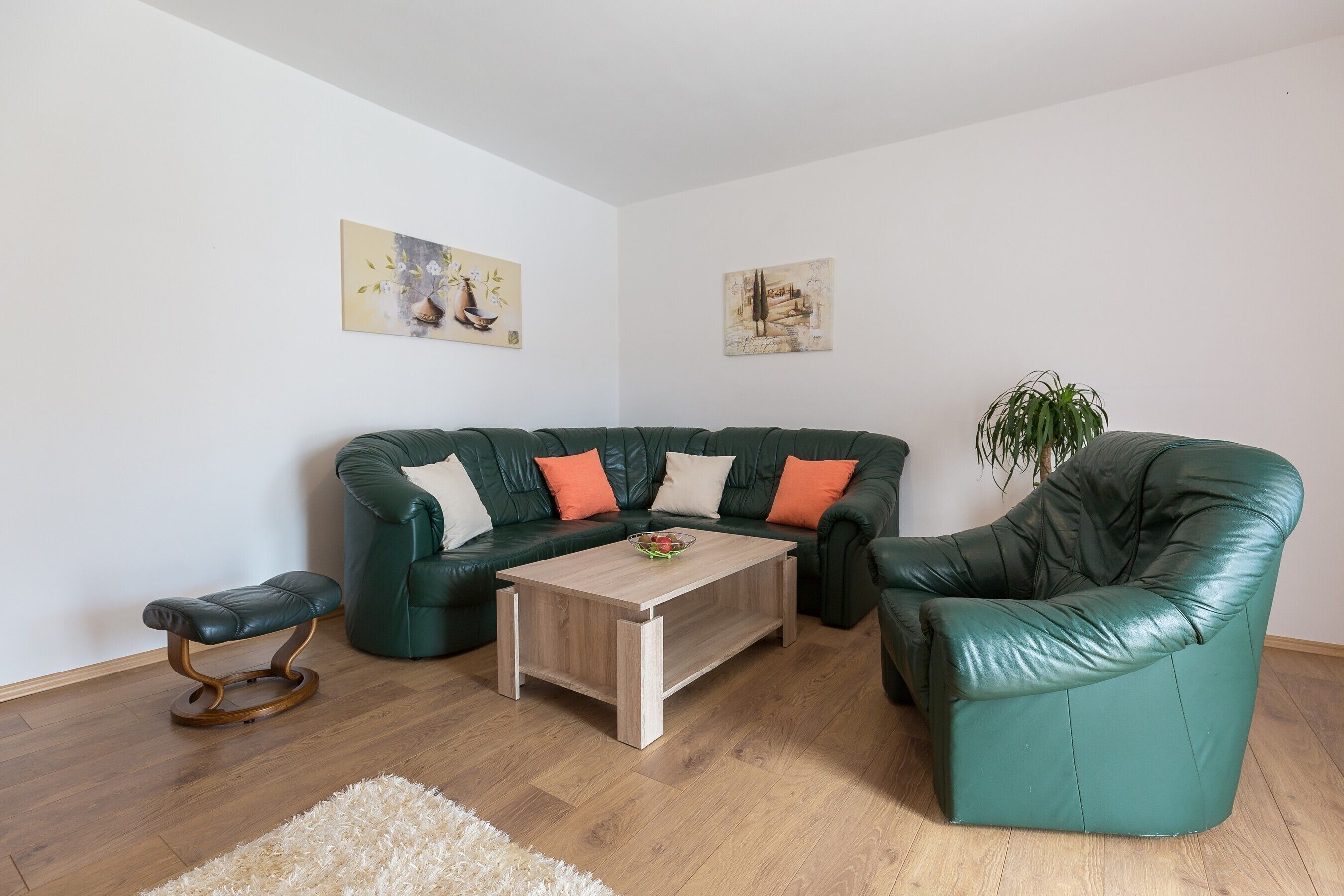 Un salón con un sofá de cuero verde, una mesa de centro de madera y un pequeño banco.