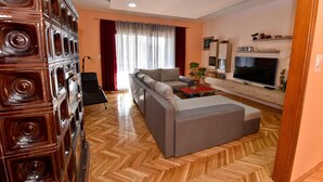 A modern living room with a sofa, a TV, and a wooden cabinet. - Holiday Agava - Three Bedroom Apartment With terrace (Razanac)