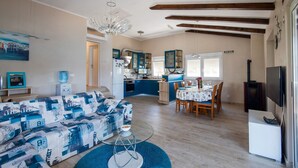 A modern living room with a sofa, a glass coffee table, and a dining area with a table and chairs. - NOSTALGIJA three bedroom holiday home with sea view terrace (Brgulje)