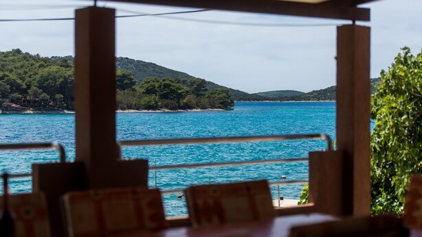 A restaurant with outdoor seating overlooking a body of water and hills. - NOSTALGIJA three bedroom holiday home with sea view terrace (Brgulje)