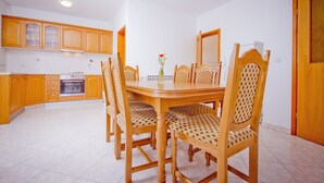 Un comedor con una mesa y sillas de madera, un florero con flores, y armarios de madera.