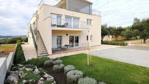 Una casa moderna de dos pisos con un balcón, una escalera y un jardín bien cuidado.