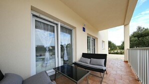 Un balcón con puerta de vidrio, un sofá y una mesa.