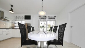Una cocina moderna con armarios blancos, una campana de acero inoxidable y una lámpara colgante negra.
