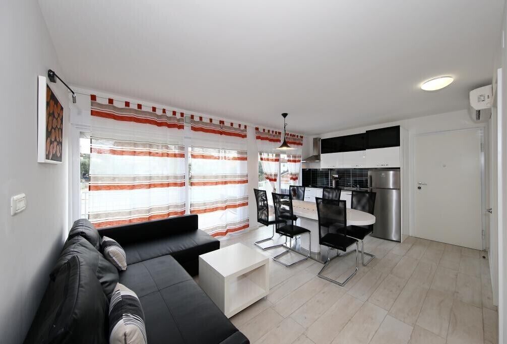 Un salon moderne avec un canapé noir, une table basse blanche et un coin repas comprenant des chaises noires et une table blanche.