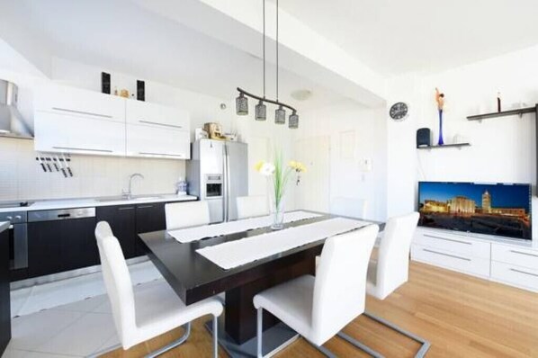 A modern kitchen with white cabinets, a black countertop, and a dining area with a white table and chairs.