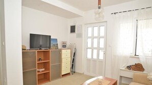 Een kamer met een televisie, houten meubels, een bureau en een raam met gordijnen.