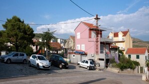 Eine Wohnstraße mit Häusern, parkenden Autos und einem wolkenlosen Himmel.