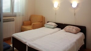 Ein Schlafzimmer mit zwei Betten, einem Sessel, einem Heizkörper und zwei Wandleuchten.