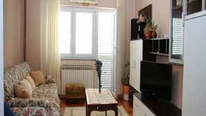 Ein Wohnzimmer mit Sofa, Tisch, Fernseher und Heizkörper.