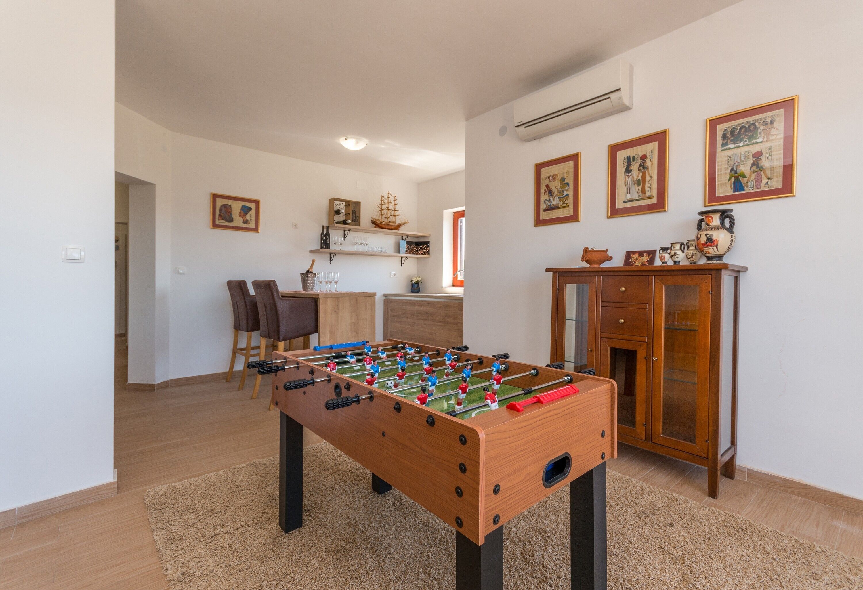 Ett mysigt vardagsrum med ett fotbollsspel, ett träskåp och en matplats i bakgrunden.