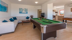 Un salon moderne avec une table de billard, un canapé et un téléviseur.