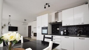 Una cocina moderna con armarios blancos, encimera negra y horno integrado.