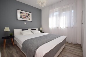 Ein modernes Schlafzimmer mit einem großen Bett, einem Nachttisch mit Lampe und einem gerahmten Kunstwerk an der Wand.