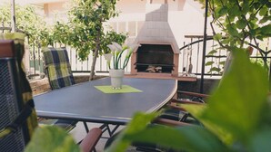 Un patio al aire libre con una mesa redonda, sillas, una planta en maceta y un horno de leña.