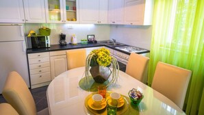 Una cocina compacta con armarios blancos, una mesa de comedor con sillas amarillas y un jarrón con flores amarillas.