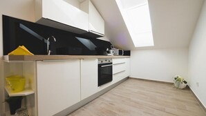 A modern kitchen with white cabinetry, a black oven, and a skylight.